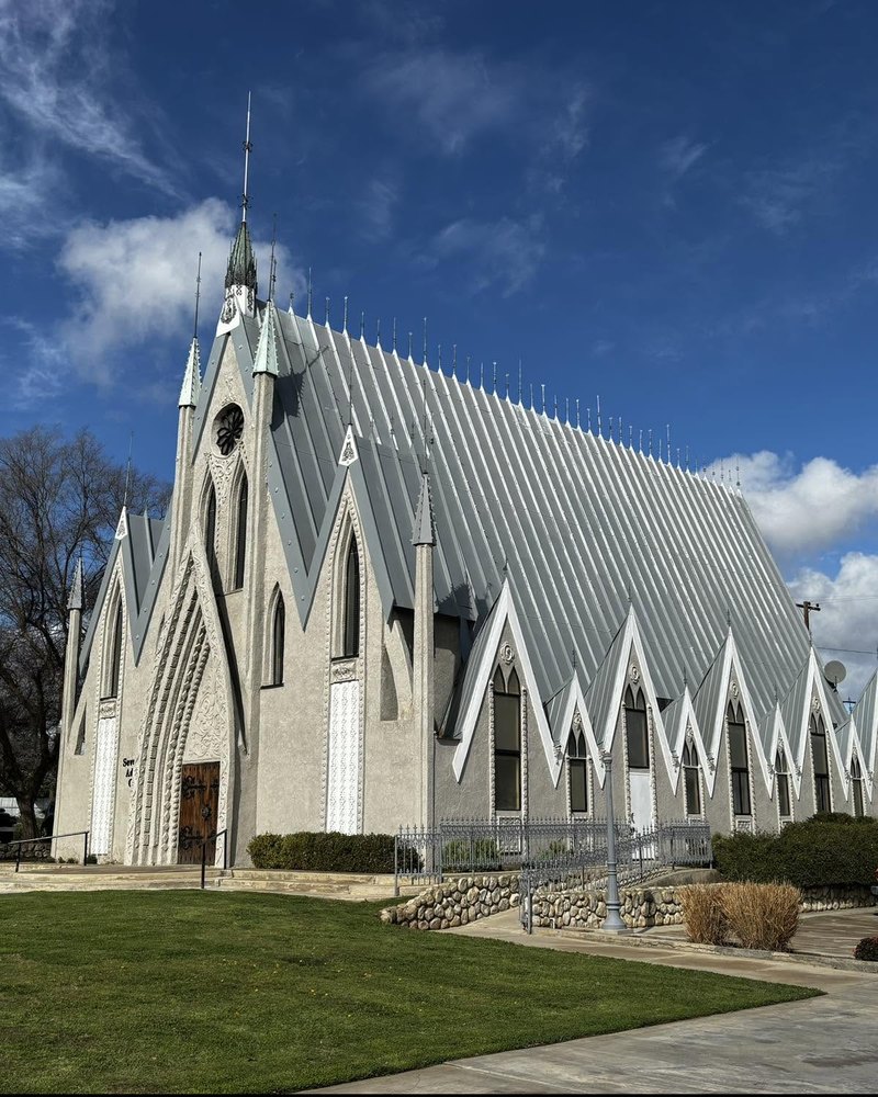 The side of Perris Seventh-day Adventist Community Church, with its tall metal roof and row of white peaked windows